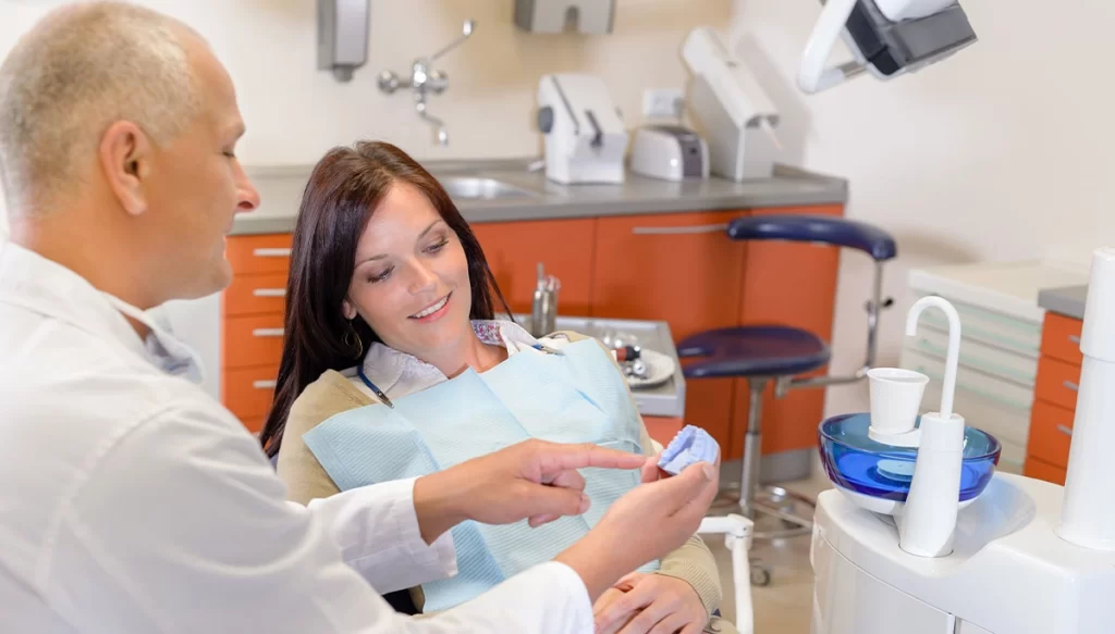 dental specialist showing model teeth to customer