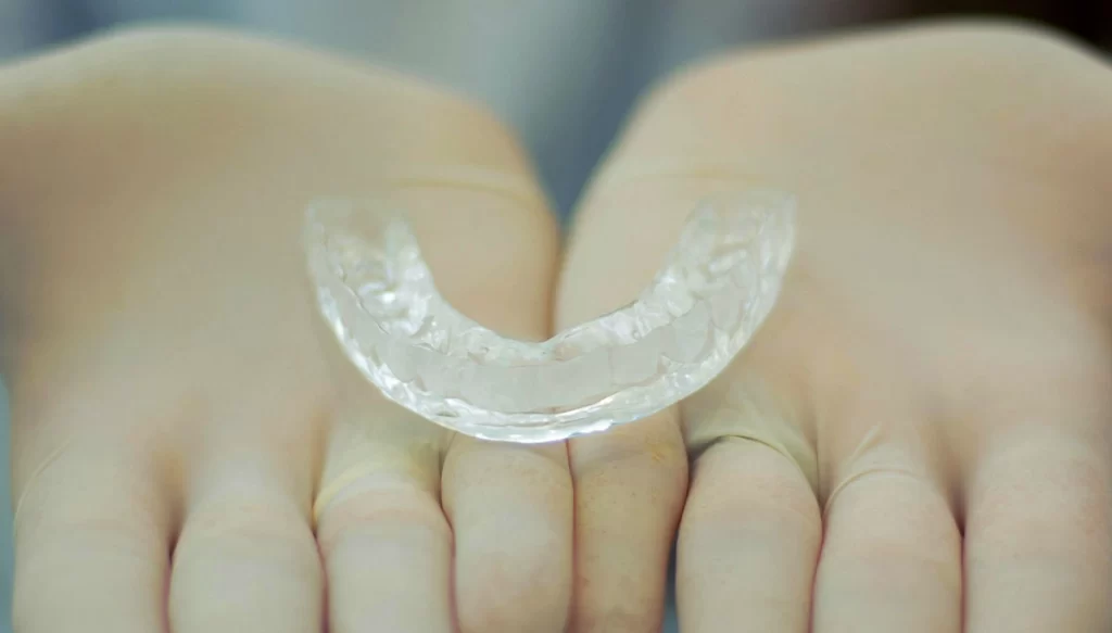 gloved hands holding A mouth guard