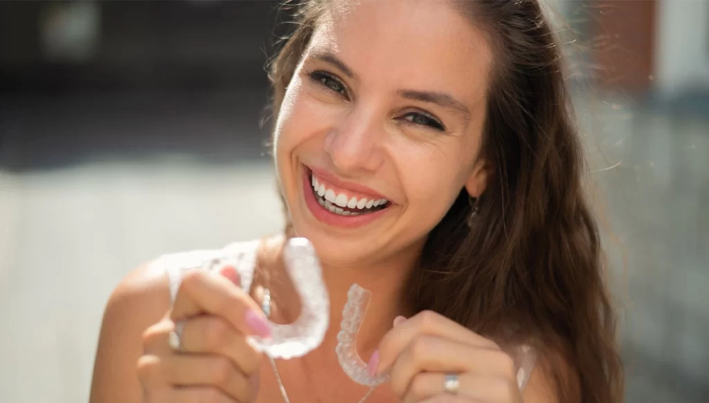 Woman smiling while holding two mouth guards