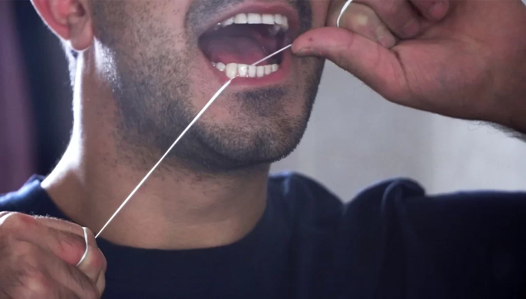 man flossing teeth in the mirror