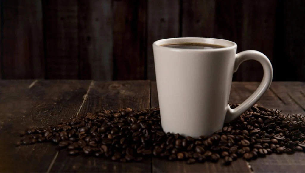 a coffee mug on a wooden table surrounded by coffee beans