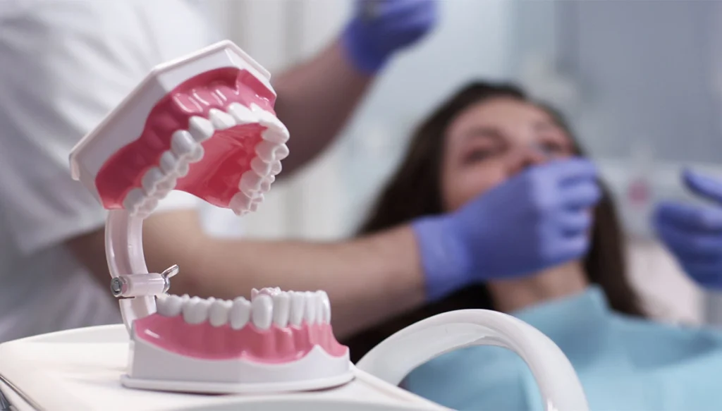 open dentures in the foreground while dentist works on patient in the background