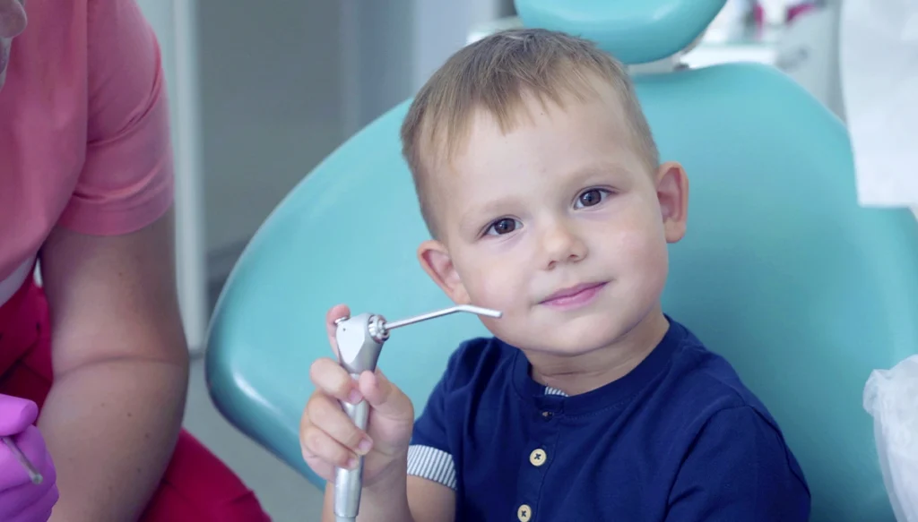 young child holds dental instrument