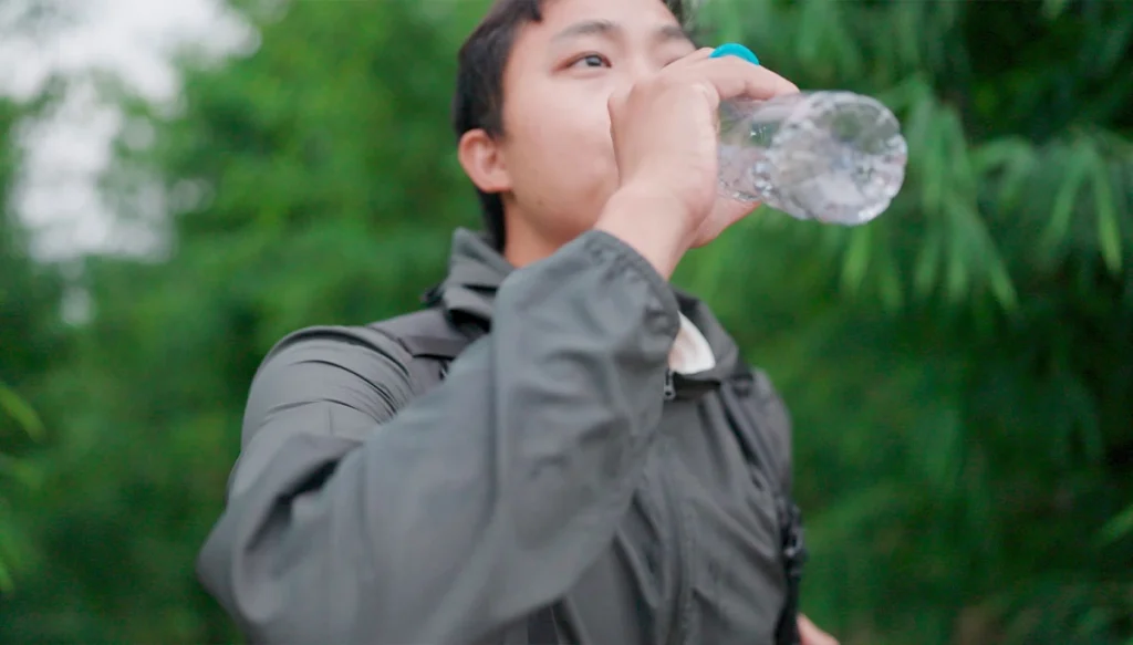 young man in a jacket drinking bottled water