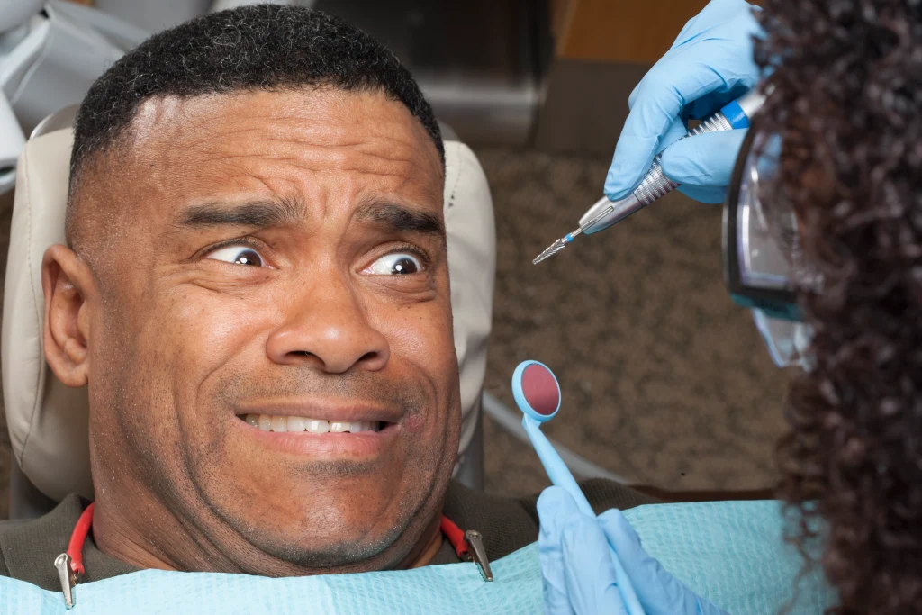 frightenned man in dentist chair looks at dentist